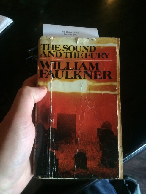 A paperback copy of William Faulkner's "The Sound and the Fury" used as a restaurant checkbook.