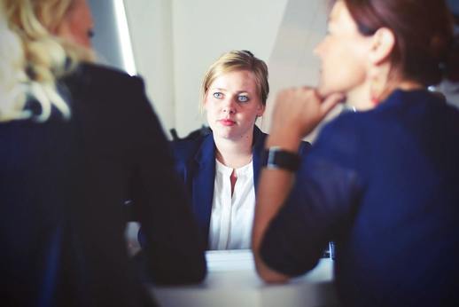 A young woman listening to two other women talking