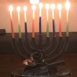 A wrought-iron menorah with a rose and chef’s knife, fully lit on the 8th night of Chanukah
