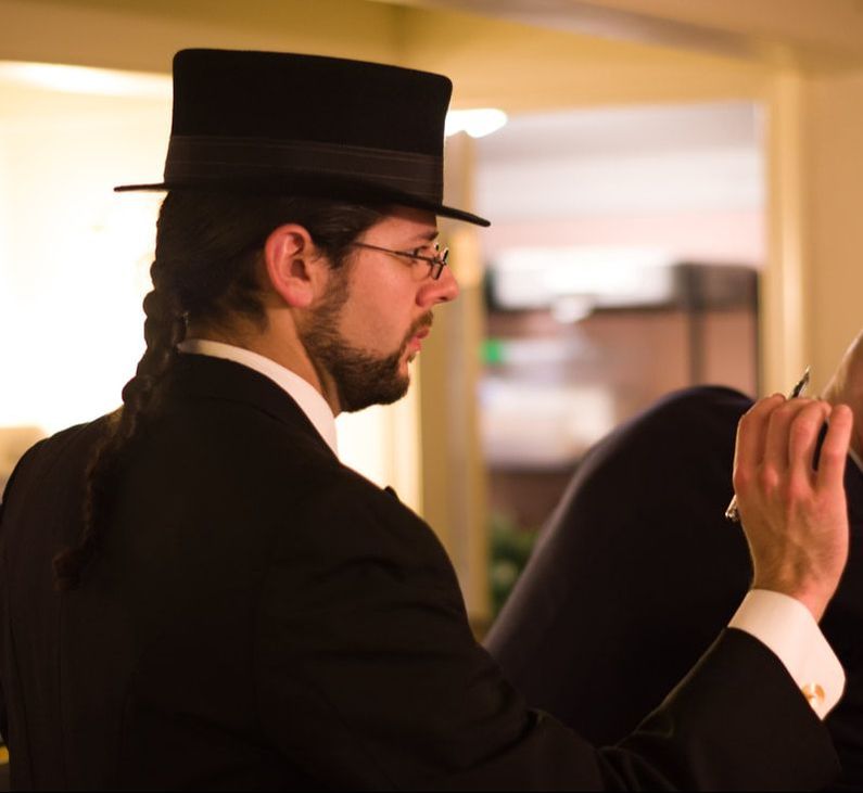 The author in a tuxedo and top hat holding a fountain pen.