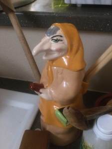 Close up of an old-fashioned ceramic spoon holder in the shape of long nosed witch in yellow