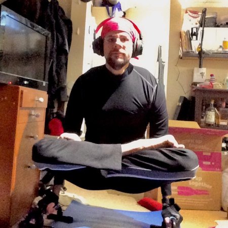 The author with his legs crossed in Lotus posture, supporting himself between two pushup bars