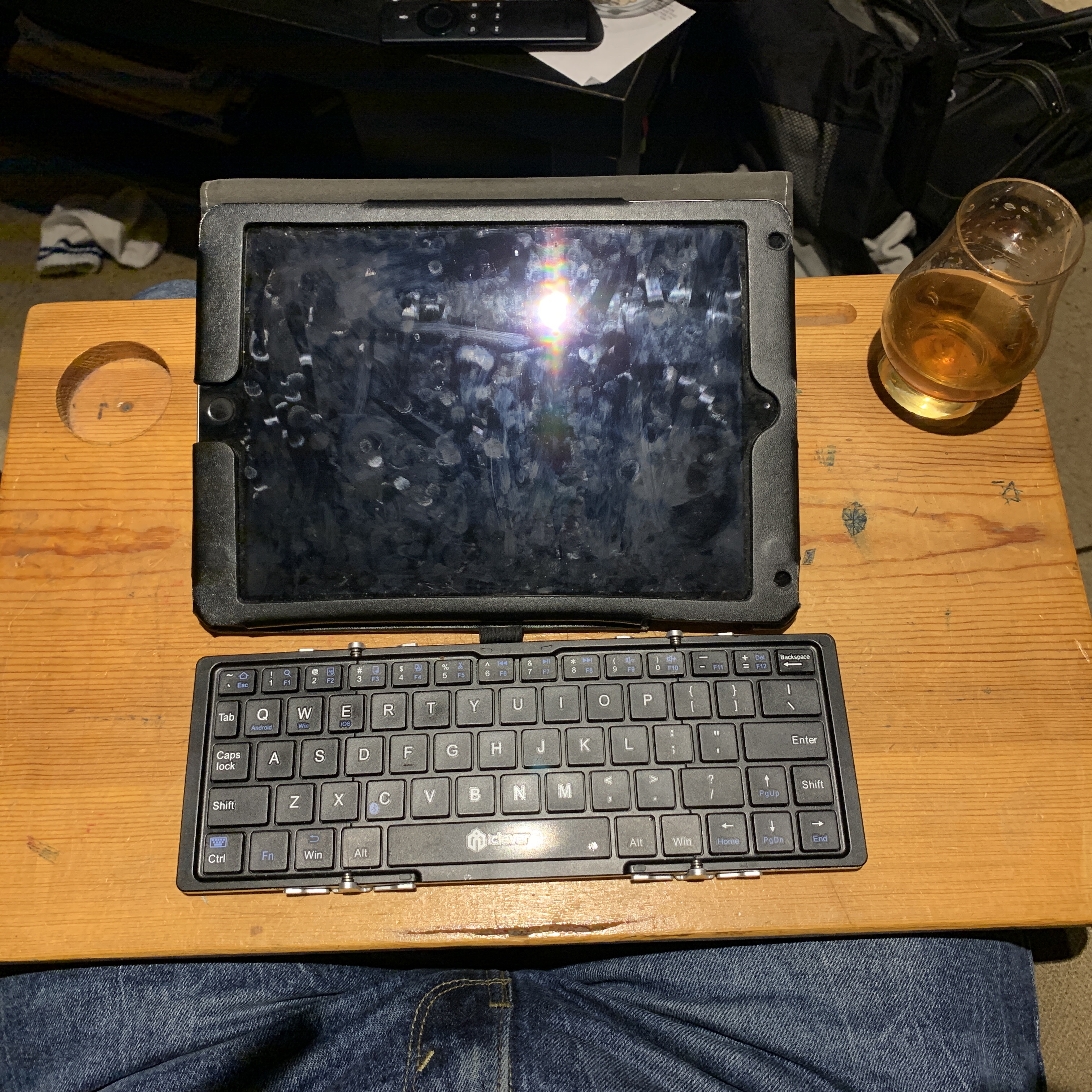 The author’s iPad, folding keyboard, and whiskey glass on a wooden lap desk.