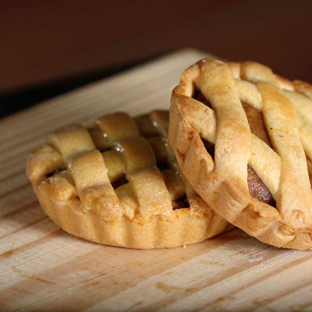 A close up of two beautifully baked tiny apple pies