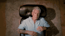 Animated GIF of Anthony Bourdain lying back on a therapists couch and putting his hands behind his head, staring straight up.