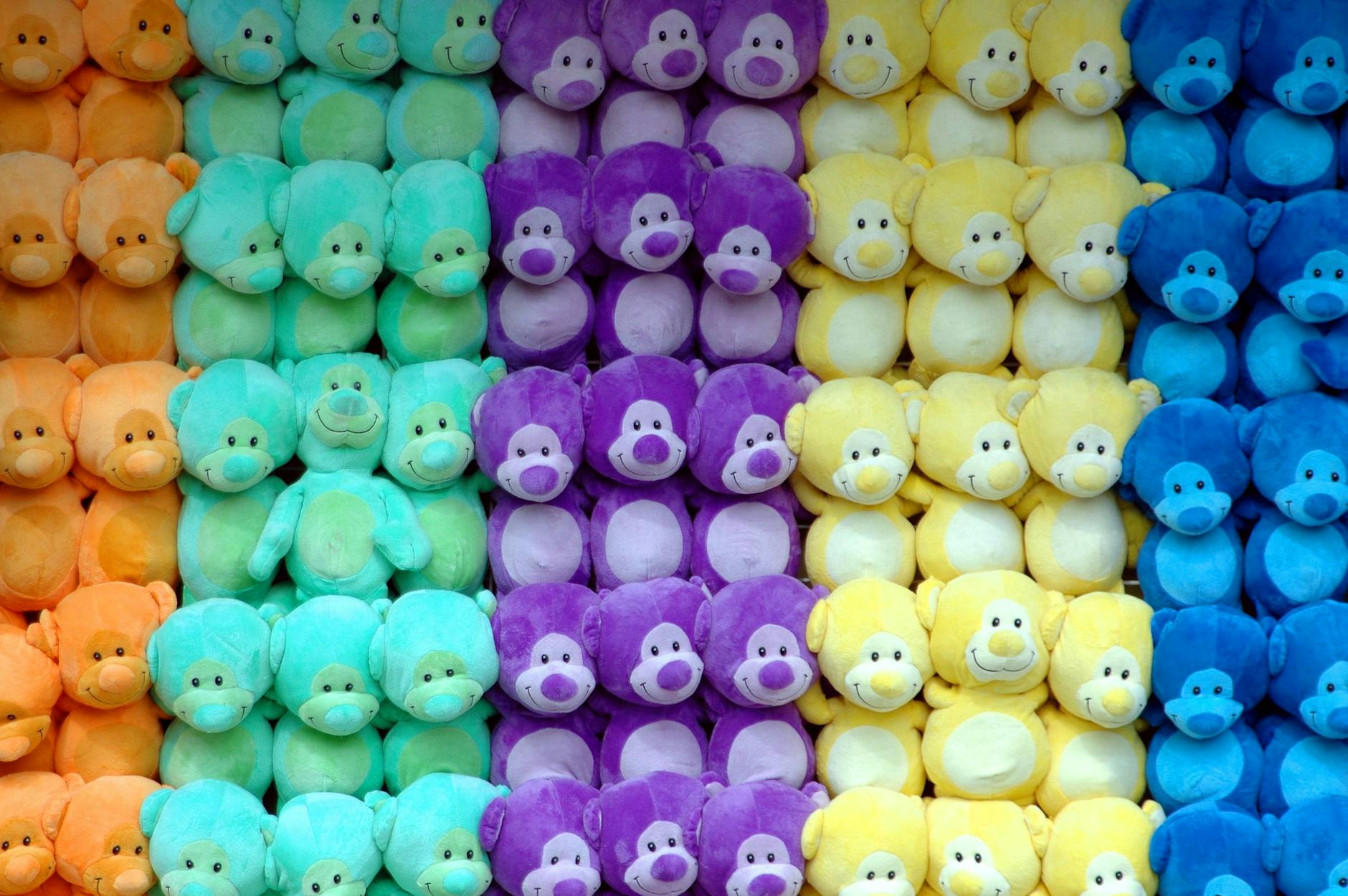 A wall of similar, multi-colored stuffed animals arranged by color.