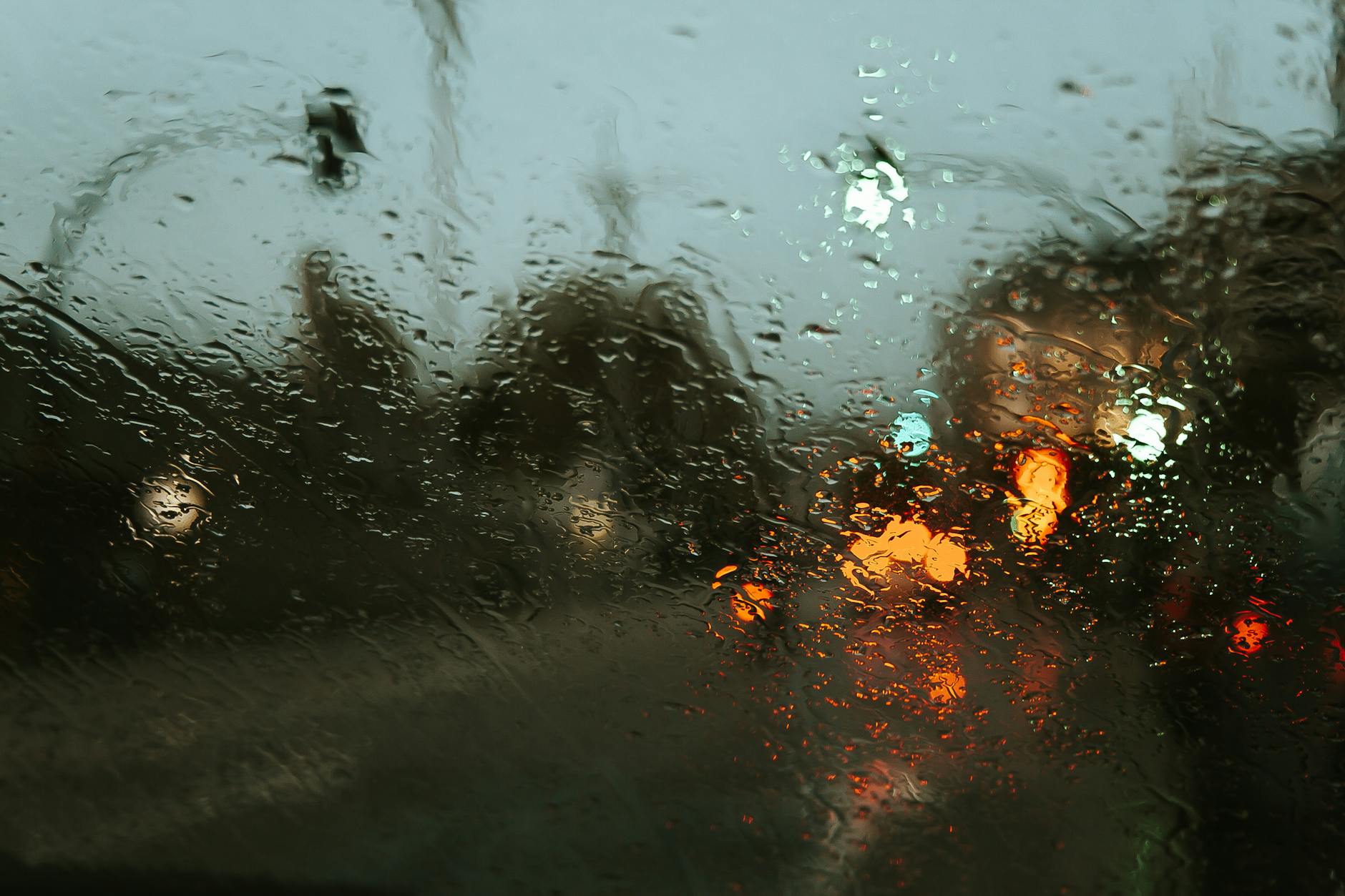 An out-of-focus picture shows an urban street seen through a rainy car window.