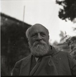 A black and white photo of Martin Buber- an elderly light-skinned man with a balding head and a bushy gray beard looking pensively into the distance.
